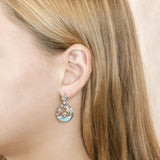 The picture shows a model wearing a 925 sterling silver larimar dolphin cove earring with topaz