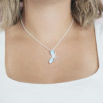 In this photo there is a model with blonde hair and a white shirt, wearing a sterling silver dragonfly pendant with blue larimar gemstones.