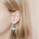 The picture shows a model wearing a 925 sterling silver larimar eagle ray hook earring.