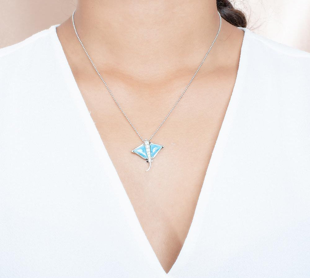 The picture shows a model wearing a 925 sterling silver larimar eagle ray pendant with cubic zirconia.