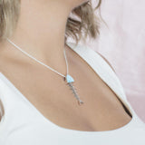The picture shows a model wearing a 925 sterling silver larimar fish bone pendant with cubic zirconia.