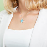 The picture shows a model wearing a 925 sterling silver larimar heart pendant.
