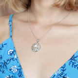 The picture shows a model wearing a 925 sterling silver one stone larimar sea turtle pendant with larimar gemstones and topaz.