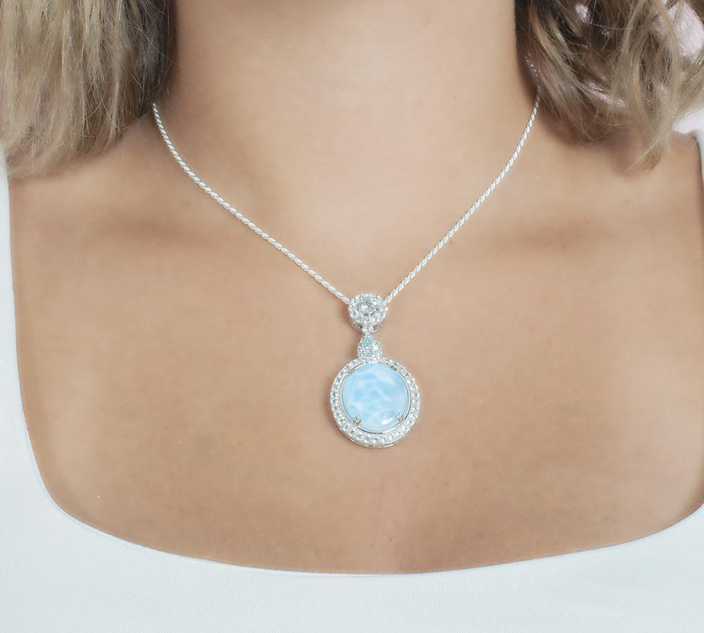 The picture shows a model wearing a 925 sterling silver larimar mirror pendant with topaz and sapphire.