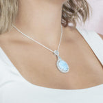The picture shows a model wearing a 925 sterling silver larimar mirror pendant with topaz and sapphire.