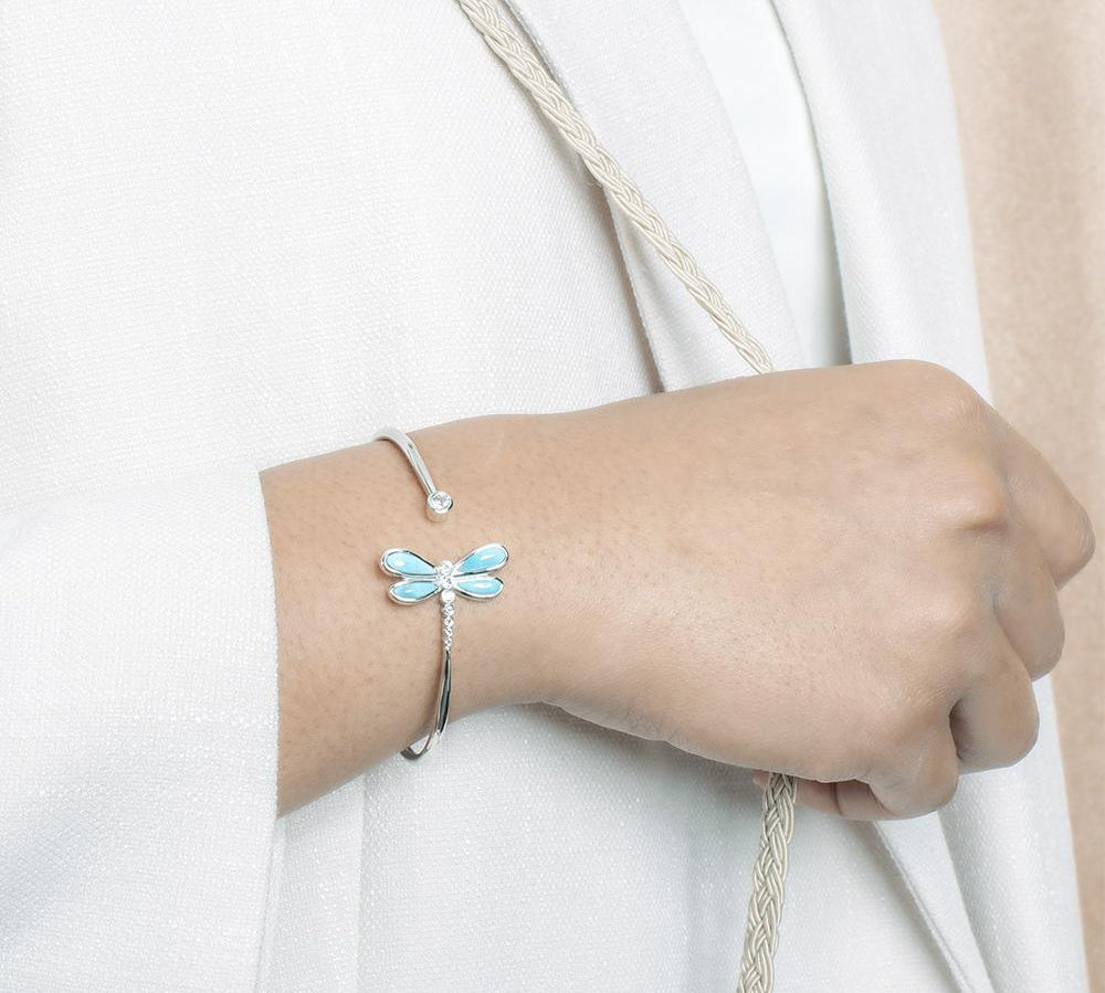 In this photo there is a model wearing a 925 sterling silver dragonfly bangle with blue larimar and aquamarine gemstones.