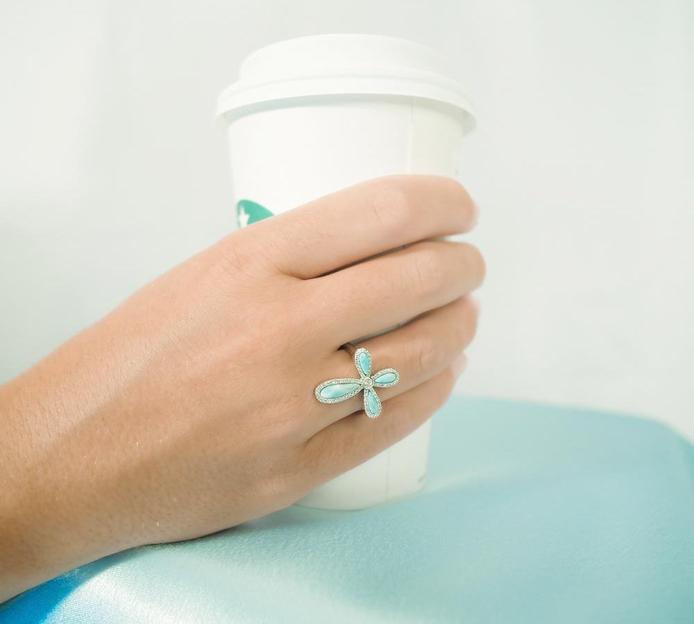 The picture shows a model wearing a 925 sterling silver larimar cross ring paired with topaz.