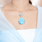 The picture shows a model wearing a 925 sterling silver larimar teardrop pendant.