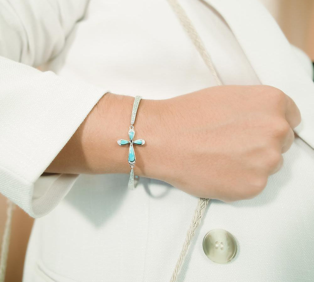 The picture shows a model wearing a 925 sterling silver larimar cross bracelet with topaz.