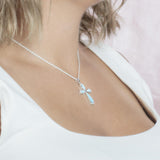 The picture shows a model wearing a 925 sterling silver larimar cross pendant with topaz.