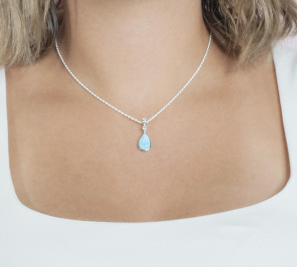 The picture shows a model wearing a 925 sterling silver larimar teardrop pendant with topaz.