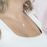 The picture shows a model wearing a 925 sterling silver larimar teardrop pendant with topaz.