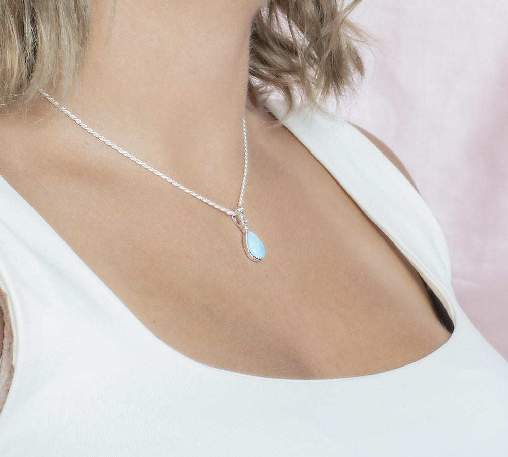 The picture shows a model wearing a 925 sterling silver larimar teardrop pendant with topaz.