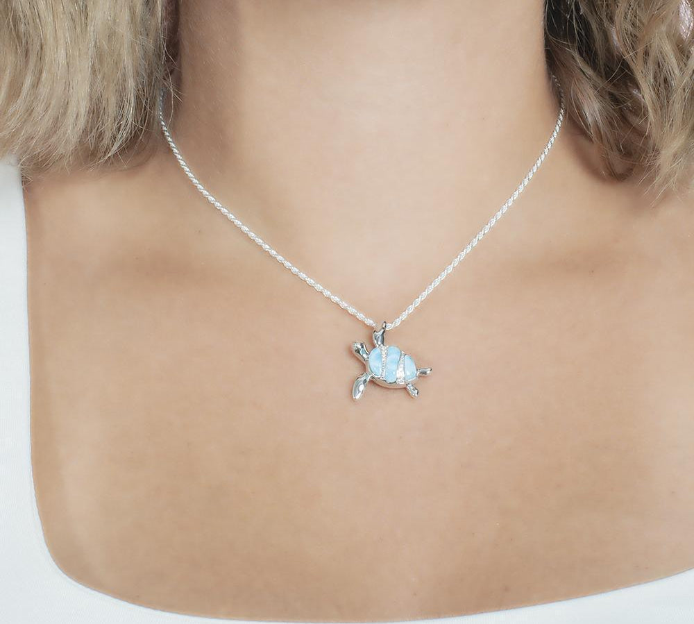 The picture shows a model wearing a 925 sterling silver larimar sea turtle pendant with topaz.