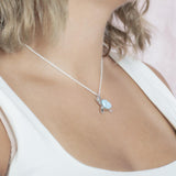 The picture shows a model wearing a 925 sterling silver larimar sea turtle pendant with topaz.