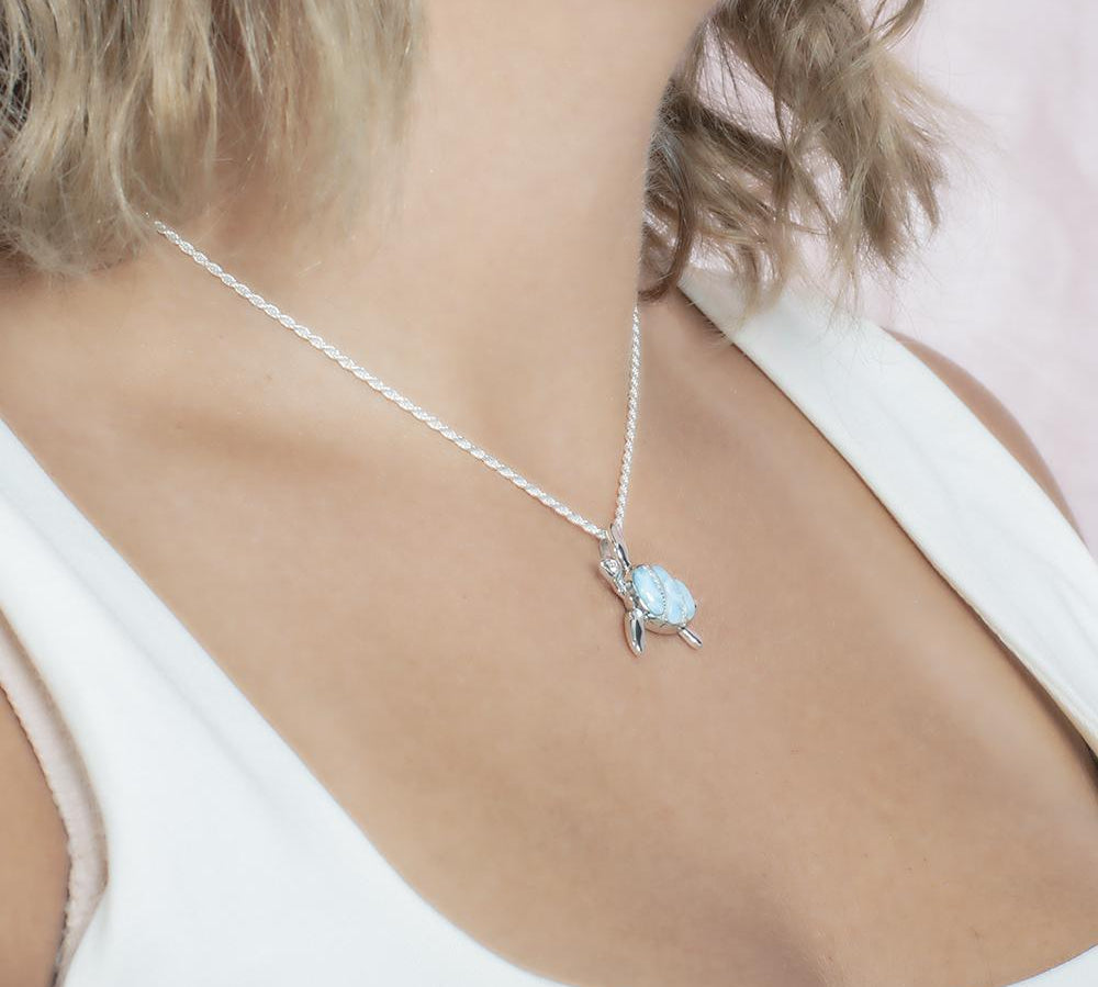 The picture shows a model wearing a 925 sterling silver larimar sea turtle pendant with topaz.