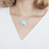 The picture shows a model wearing a 925 sterling silver larimar living sand dollar pendant.