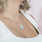 The picture shows a model wearing a 925 sterling silver larimar love potion bottle pendant with aquamarine and topaz.