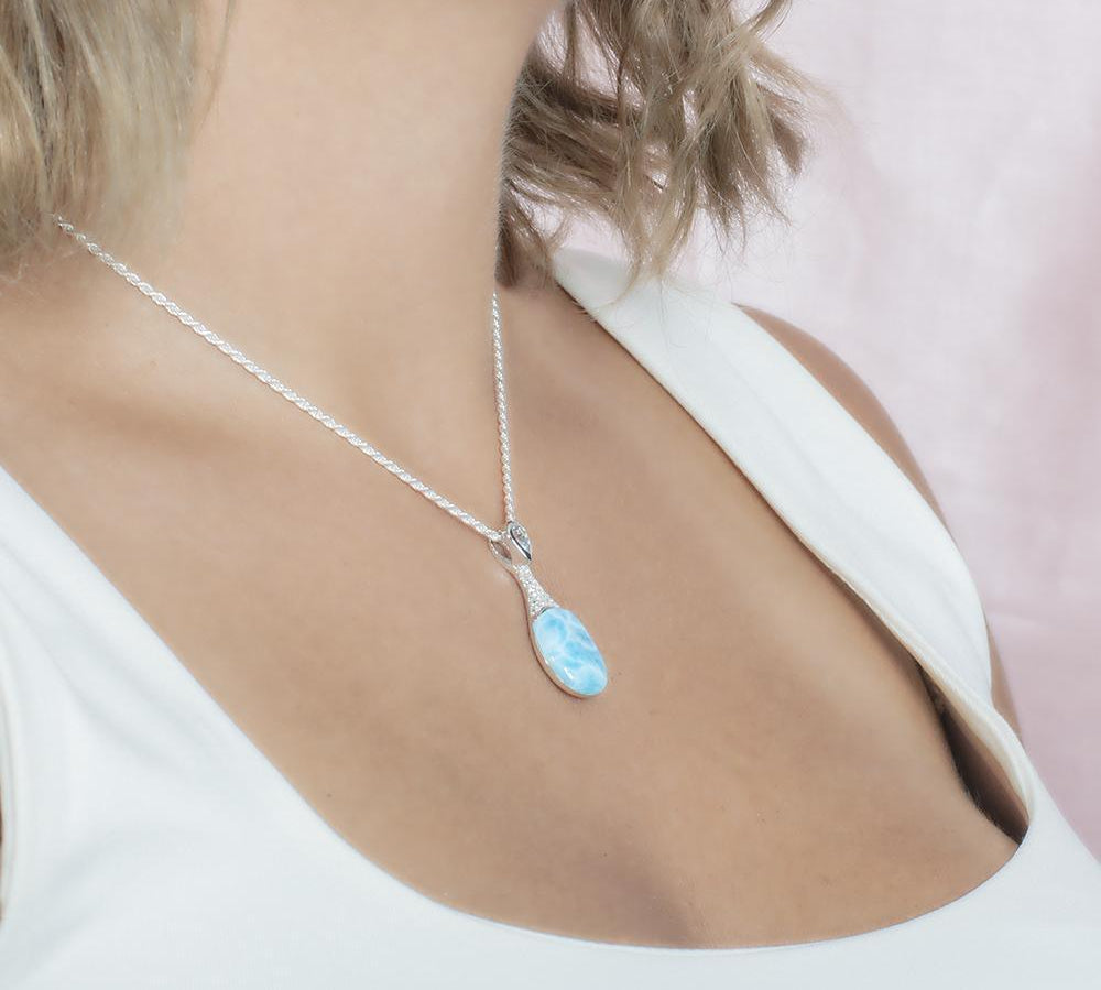 The picture shows a model wearing a 925 sterling silver larimar love potion bottle pendant with aquamarine and topaz.