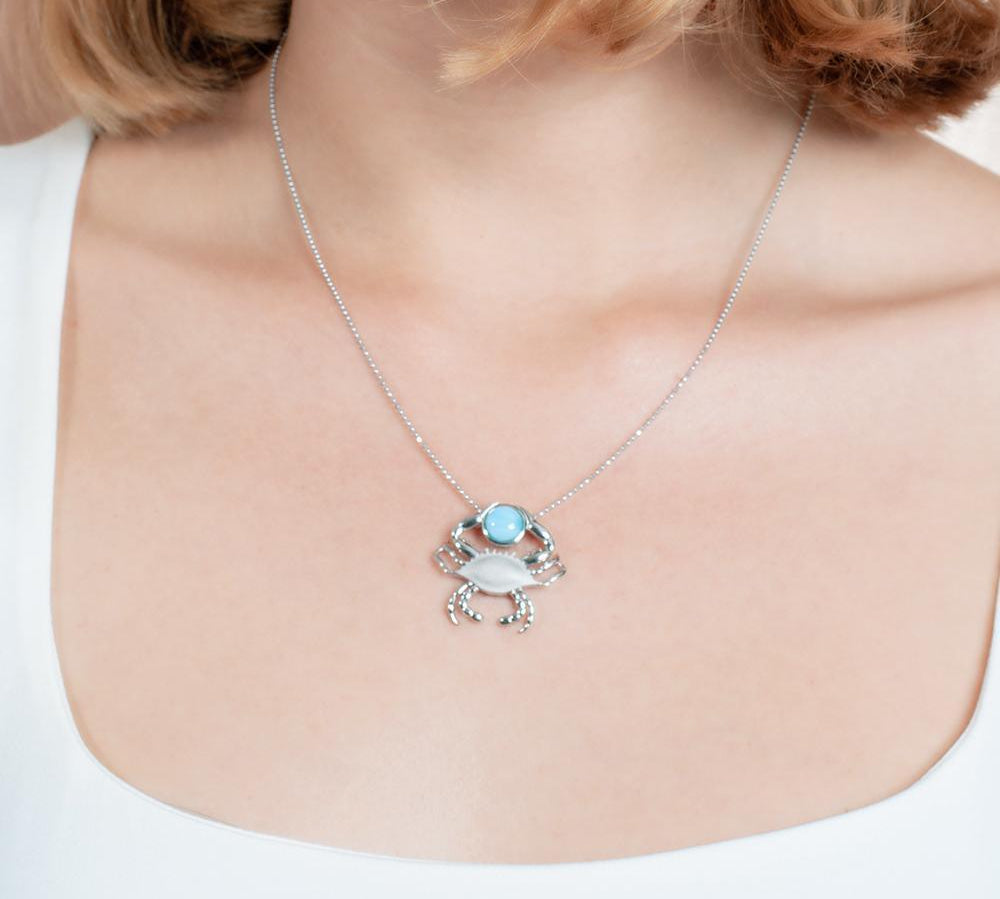 The picture shows a model wearing a 925 sterling silver larimar lucky blue crab pendant.