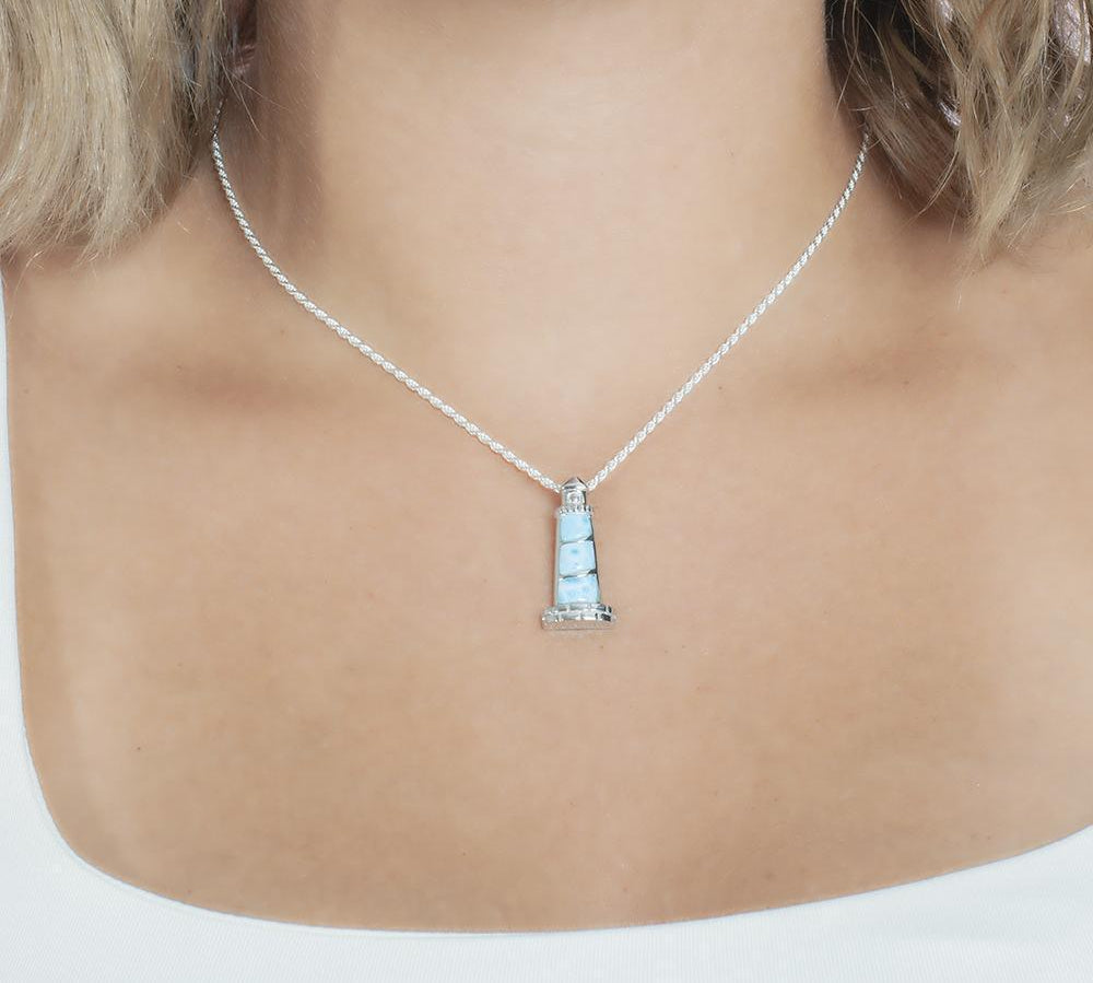 In this picture there is a model with blonde hair and a white shirt wearing a lighthouse pendant with blue larimar gemstones set in sterling silver.