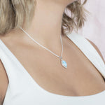 The picture shows a model wearing a 925 sterling silver larimar mandorla pendant with topaz.