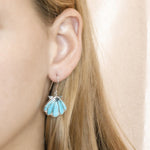 The picture shows a model wearing a 925 sterling silver larimar mermaid's oyster shell hook earring.