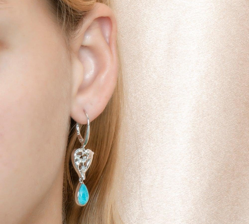 The photo shows a model wearing a larimar sterling silver earring featuring our dolphin design. 