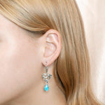 The photo shows a model wearing a larimar sterling silver earring featuring our dolphin design. 