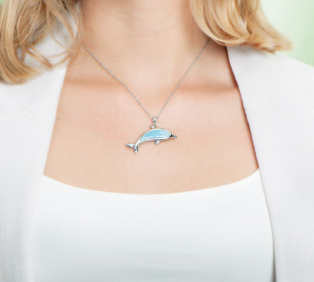 The picture shows a model wearing a 925 sterling silver larimar dolphin pendant.