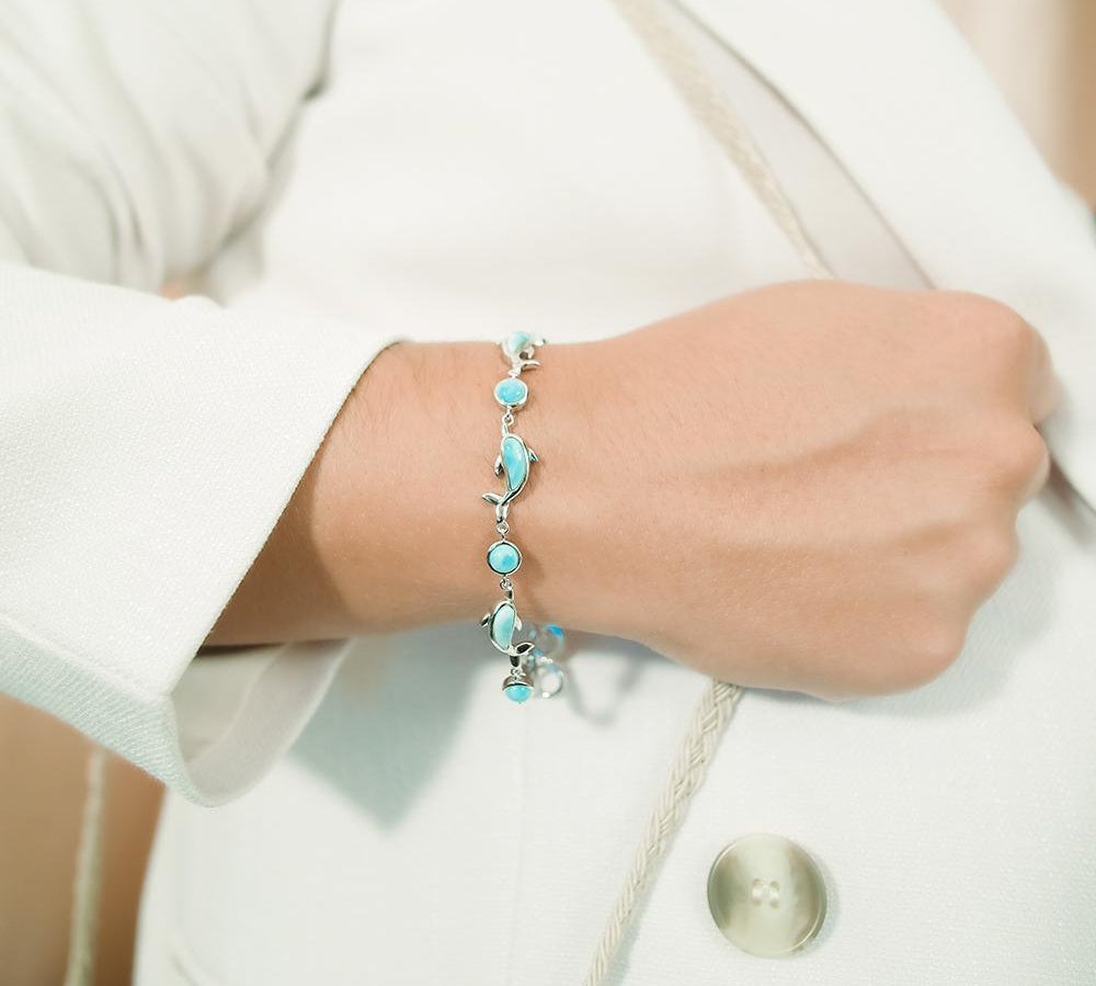 The picture shows a model wearing a 925 sterling silver larimar dolphin bracelet.