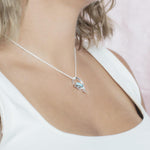 The picture shows a model wearing a 925 sterling silver larimar dolphin through circle pendant with topaz.