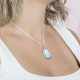 The picture shows a model wearing a 925 sterling silver larimar teardrop pendant.