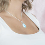 The picture shows a model wearing a 925 sterling silver larimar teardrop pendant.