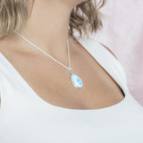 The picture shows a model wearing a 925 sterling silver larimar teardrop pendant.