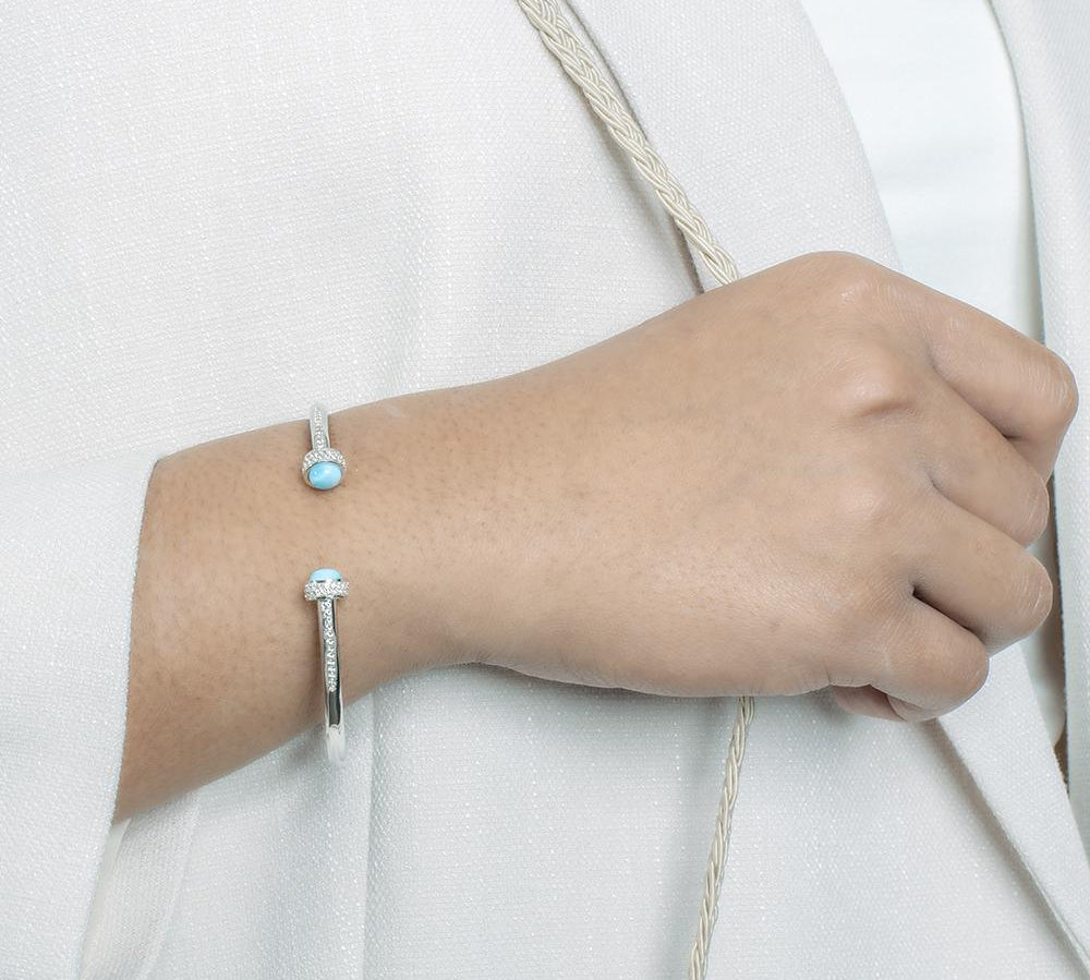 The picture shows a model wearing a 925 sterling silver larimar bangle with topaz.