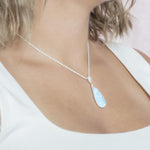 The picture shows a model wearing a 925 sterling silver larimar teardrop pendant with topaz.