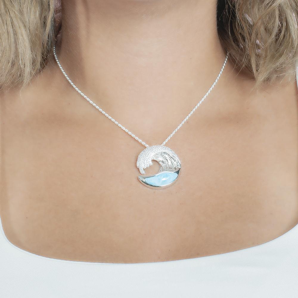 The picture shows a model wearing a 925 sterling silver larimar ocean wave pendant with topaz.