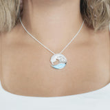 The picture shows a model wearing a 925 sterling silver larimar ocean wave pendant with topaz.