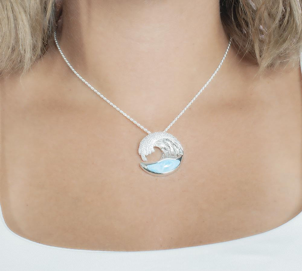 The picture shows a model wearing a 925 sterling silver larimar ocean wave pendant with topaz.