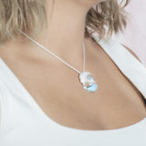 The picture shows a model wearing a 925 sterling silver larimar ocean wave pendant with topaz.