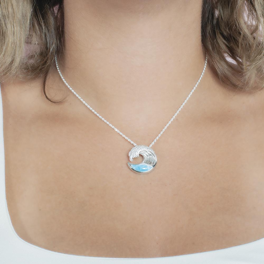 The picture shows a model wearing a 925 sterling silver larimar ocean wave pendant with topaz.