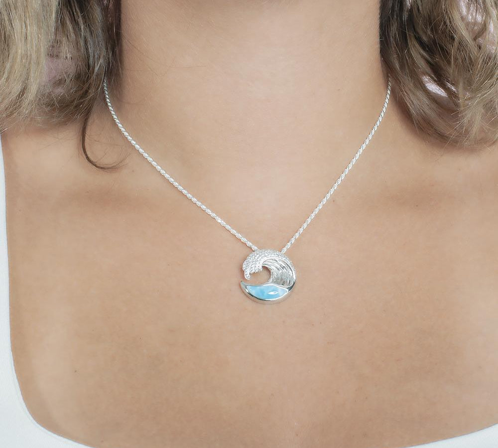 The picture shows a model wearing a 925 sterling silver larimar ocean wave pendant with topaz.