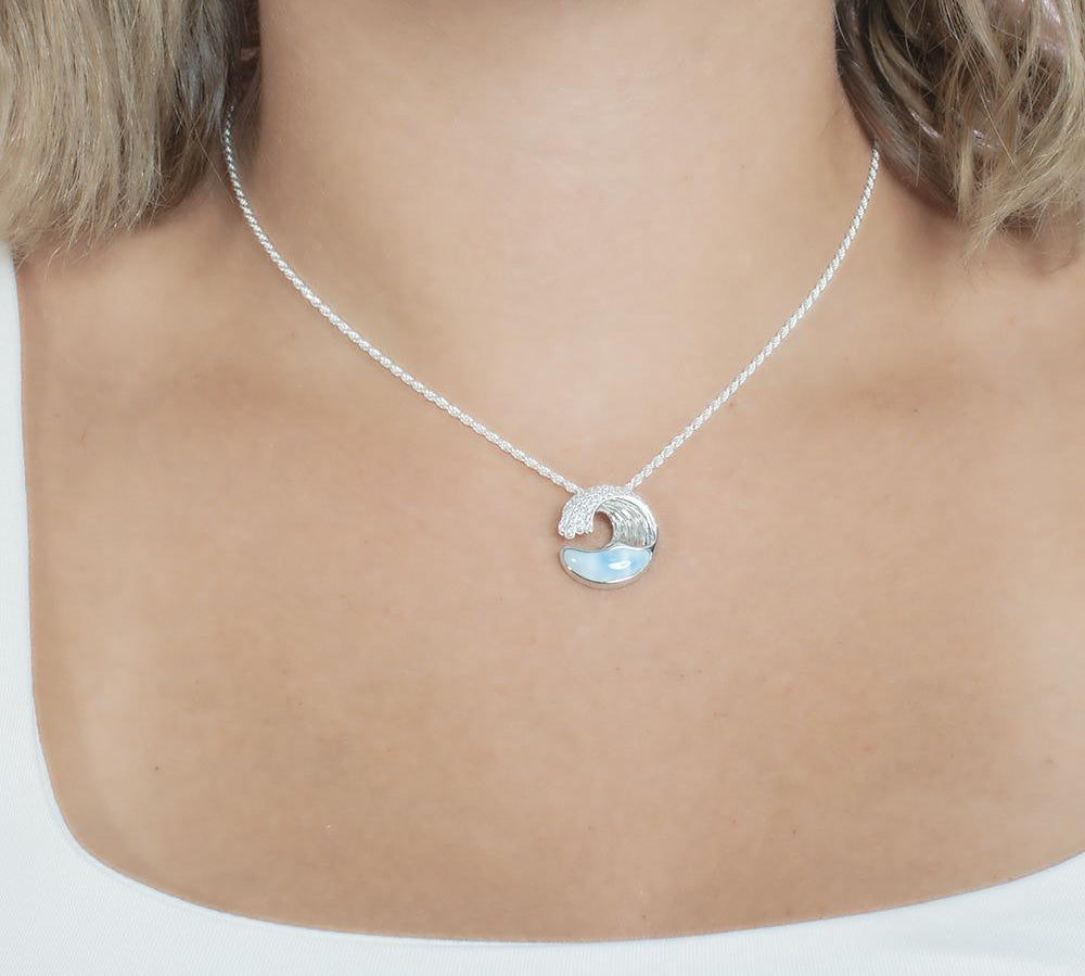 The picture shows a model wearing a 925 sterling silver larimar ocean wave pendant with topaz.
