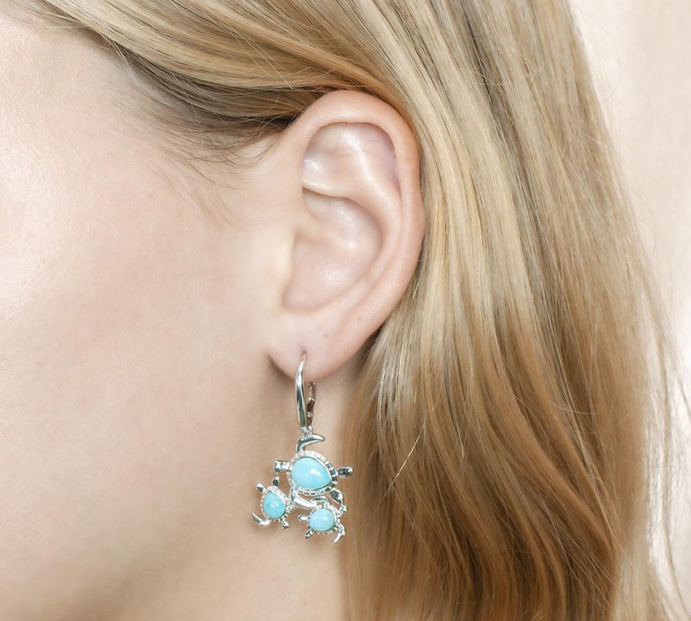The picture shows a model wearing a 925 sterling silver larimar sea turtles lever-back earring.