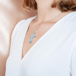 The picture shows a model wearing a 925 sterling silver larimar and opalite cross pendant.
