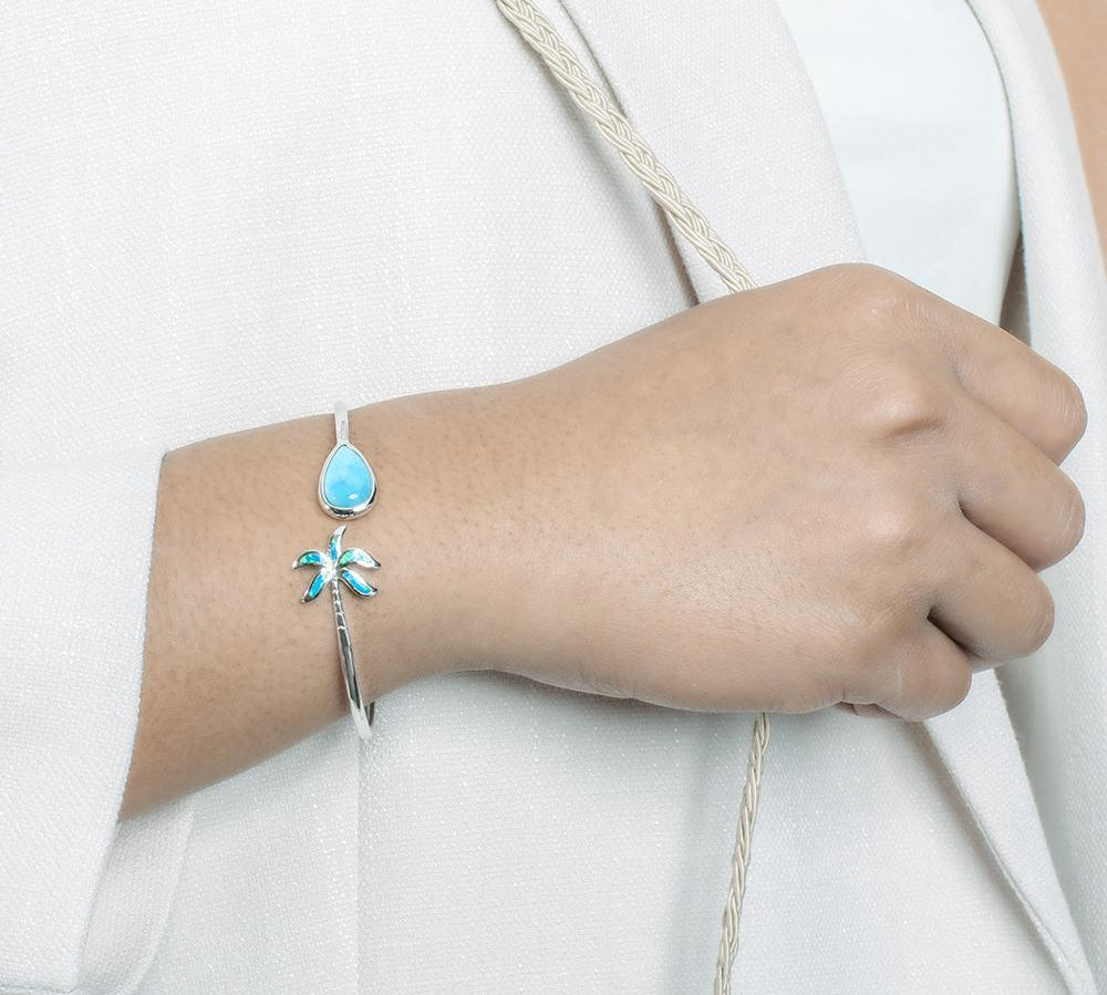 This photo shows a model wearing a 925 sterling silver larimar teardrop and opalite palm tree banle