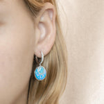 The picture shows a model wearing a 925 sterling silver larimar and opalite lever-back earrings