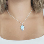The picture shows a model wearing a 925 sterling silver larimar oval pendant.