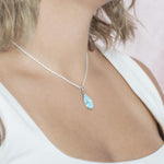 The picture shows a model wearing a 925 sterling silver larimar pieces of love teardrop pendant with cubic zirconia.